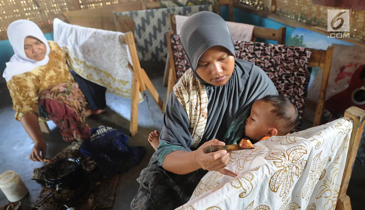 Seorang ibu menyusui anaknya sambil membuat batik tulis di Kampung Batik Puswasedar kawasan Geopark Ciletuh, Sukabumi, Jawa Barat, Sabtu (22/9). Sebelum menekuni pembuatan batik, para perempuan berprofesi sebagai petani. (Merdeka.com/Arie Basuki)
