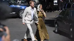 Duchess of Sussex Meghan Markle menggandeng tangan suaminya, Pangeran Harry saat tiba di Masjid Auwal, Cape Town, Afrika Selatan (24/9/2019). Meghan tampil dengan gaun hijau berlengan pendek dengan memadukan kerudung coklat mudanya. (AFP Photo/David Harrison)