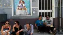 Warga duduk di samping mural yang terinspirasi oleh karya Velazquez "Las Meninas" selama festival seni jalanan tahunan di Ferrol, Spanyol, Minggu (2/9). (MIGUEL RIOPA/AFP)