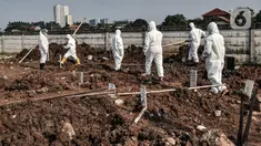 Petugas Sudin Pertamanan dan Hutan Kota Jakarta Utara mengenakan baju hazmat bersiap memakamkan jenazah pasien Covid-19 di TPU Rorotan, Jakarta, Minggu (28/3/2021). TPU Rorotan mulai difungsikan sebagai tempat pemakaman jenazah pasien Covid-19 ber-KTP DKI Jakarta. (merdeka.com/Iqbal S. Nugroho)