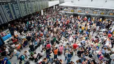 Calon penumpang berkumpul di depan papan jadwal penerbangan di Terminal 2 Bandara Munich, Sabtu (28/7). Kepolisian Jerman menutup terminal 2 bandara tersebut setelah seorang wanita dilaporkan menyusup melewati pos pemeriksaan. (MATTHIAS BALK /DPA/AFP)