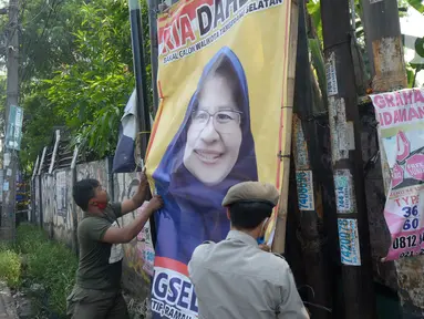 Petugas Satpol PP menertibkan Alat Peraga Kampanye (APK) bakal calon Wali Kota dan Wakil Wali Kota Tangerang Selatan di sepanjang jalan raya di Kota Tangerang Selatan, Kamis (27/8/2020). Semua poster dan baliho diturunkan karena tidak memiliki izin dan masa izin telah habis. (merdeka.com/Dwi Narwoko