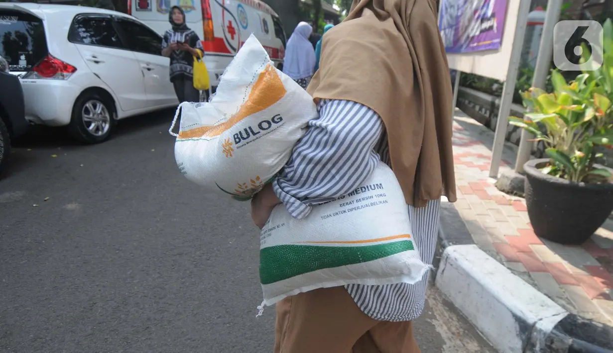 Warga berjalan dengan membawa beras kemasan 10 kilogram di Kelurahan Pela Mampang, Jakarta, Jumat (3/5/2024). (merdeka.com/Imam Buhori)