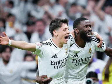 Pemain Real Madrid, Arda Guler dan Antonio Rudiger, merayakan kemenangan atas Real Sociedad pada laga semifinal Copa Del Rey di Stadion Santiago Bernabeu, Rabu (2/4/2025). (AP Photo/Bernat Armangue)
