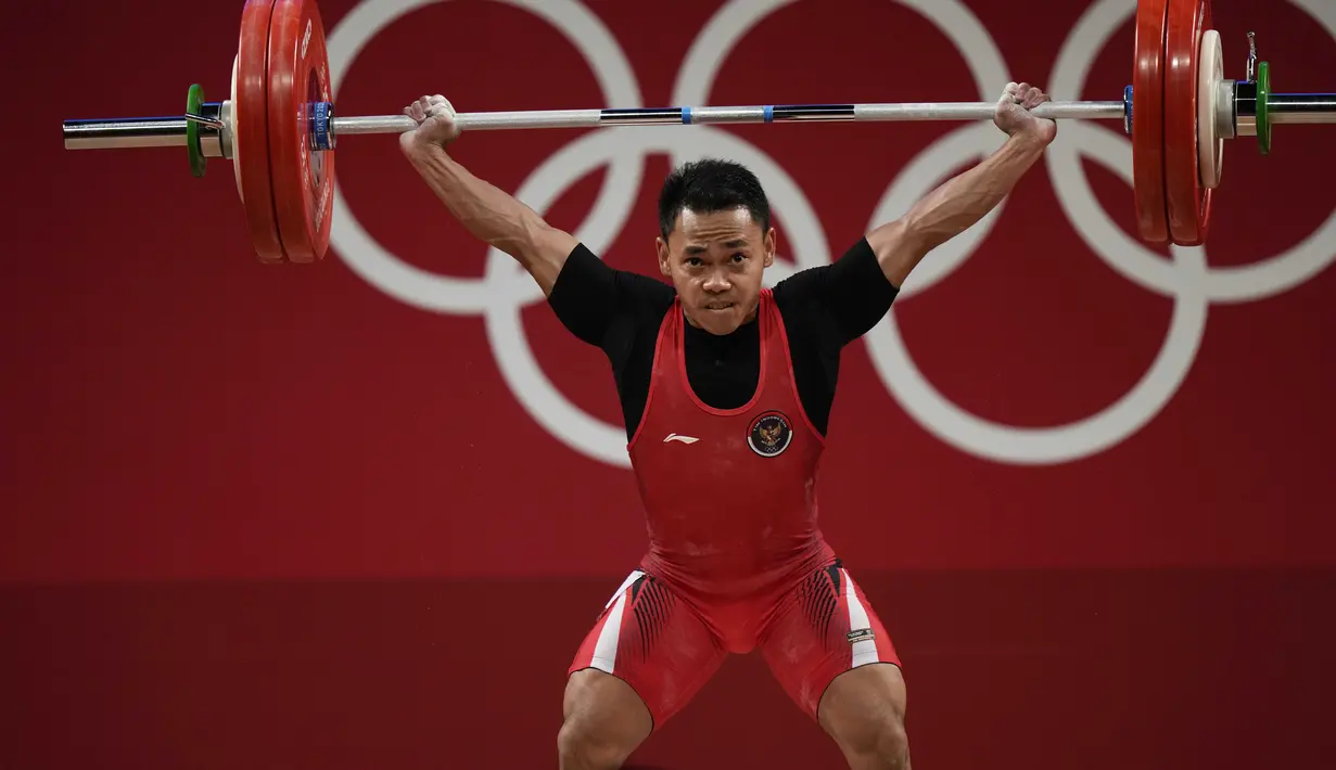 Lifter andalan Indonesia, Eko Yuli Irawan melakukan angkatan snatch dalam kelas 61kg putra Grup A cabor angkat besi Olimpiade Tokyo 2020 di Tokyo International Forum, Minggu (25/7/2021). Eko Yuli meraih medali perak dengan total angkatan 302 kg. (AP Photo/Luca Bruno)