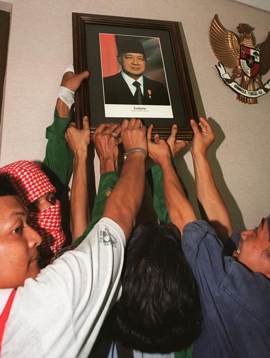 Mahasiswa mencopot foto Presiden Soeharto di gedung parlemen Senayan, Jakarta pada 21 Mei 1998. Soeharto yang telah telah menjadi presiden Indonesia selama 32 tahun mundur setelah runtuhnya dukungan untuk dirinya. KEMAL JUFRI/AFP)