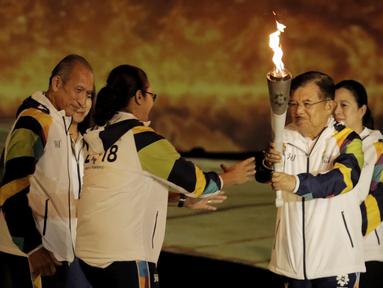 Wapres RI, Jusuf Kalla, menyerahkan api obor kepada pebulutangkis asal Yogyakarta, Kinarsih, saat prosesi kirab obor di Candi Prambanan, Rabu (18/7/2018). Api obor Asian Games tersebut akan dibawa mengelilingi 18 provinsi. (Bola.com/M Iqbal Ichsan)