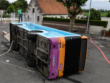 Seorang pria bekerja pada bus kota yang diubah menjadi kolam renang di Gosnay, Prancis Utara pada 15 Juli 2019. Karya seorang seniman Prancis, Benedetto Bufalino ini merupakan bus yang sudah dipensiunkan alias tak layak pakai untuk mengaspal di jalanan kota. (DENIS CHARLET / AFP)