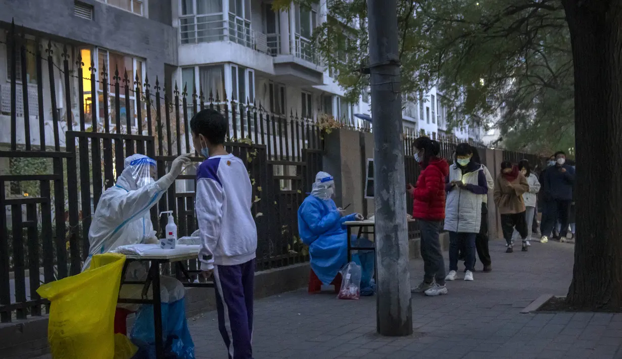 Seorang pekerja yang mengenakan pakaian pelindung melakukan tes COVID-19 kepada seorang anak laki-laki di tempat pengujian virus corona di Beijing, Rabu (9/11/2022). Lonjakan kasus COVID-19 telah mendorong penguncian di pusat manufaktur China selatan Guangzhou, menambah keuangan tekanan yang telah mengganggu rantai pasokan global dan secara tajam memperlambat pertumbuhan ekonomi terbesar kedua di dunia itu. (Foto AP/Mark Schiefelbein)