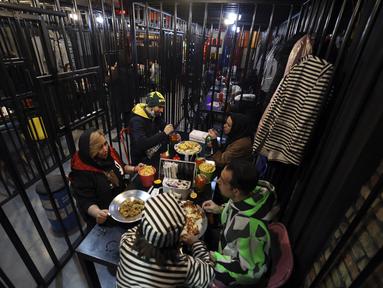 Pengunjung makan malam di restoran berkonsep penjara "Sel 16" di Teheran, 4 Februari 2022. Sebagian hasil bisnis digunakan untuk membebaskan mereka yang mendekam di penjara karena utang yang belum dibayar dimana lebih dari 11.000 warga Iran dipenjara karena gagal membayar utang. (ATTA KENARE/AFP)