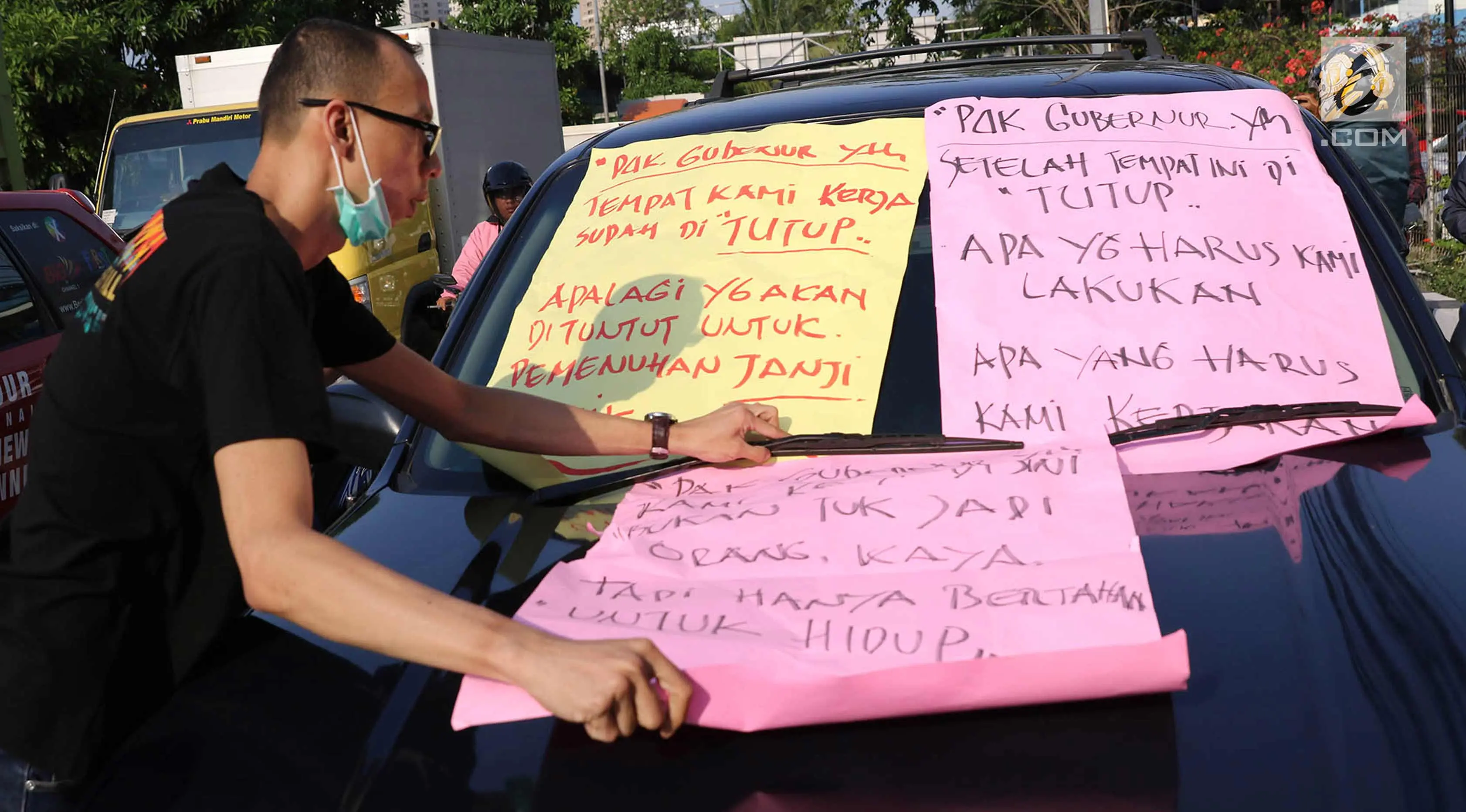 Karyawan Hotel Alexis menempelkan poster tuntutan di mobil Satpol PP saat unjuk rasa di Jakarta Utara, Kamis (29/3). Penutupan terkait kasus dugaan adanya praktek prostitusi dan perdagangan manusia di hotel tersebut. (Liputan6.com/Immanuel Antonius)