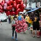 Penjual balon berbentuk hati menjajakan dagangannya di pasar bunga di Manila, Filipina, Senin (13/2/2023). Harga bunga naik karena tingginya permintaan sehari sebelum Hari Valentine. (AP Photo/Aaron Favila)