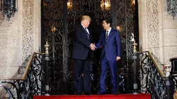 Presiden AS, Donald Trump menyambut kedatangan PM Jepang Shinzo Abe dalam pertemuan mereka di Resor Mar-a-Lago, Florida, Selasa (17/4). Pertemuan digunakan untuk mencari pemahaman bersama mengenai masalah nuklir Korea Utara. (AP/Pablo Martinez Monsivais)