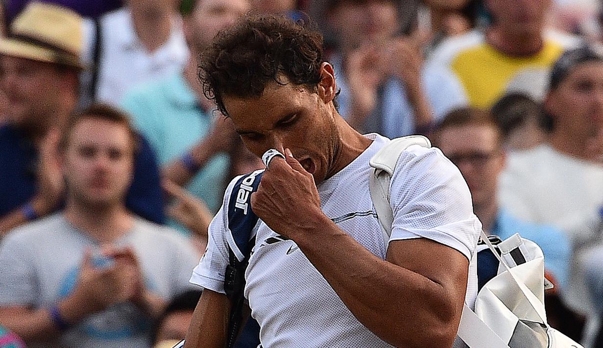 Petenis Spanyol, Rafael Nadal, bereaksi sebelum meninggalkan lapangan usai dikalahkan petenis asal Luksemburg, Giller Muller, di perempat final Wimbledon 2017, Senin (10/7). Nadal disingkirkan petenis unggulan ke-16 asal Luksemburg. (Glyn KIRK / AFP)