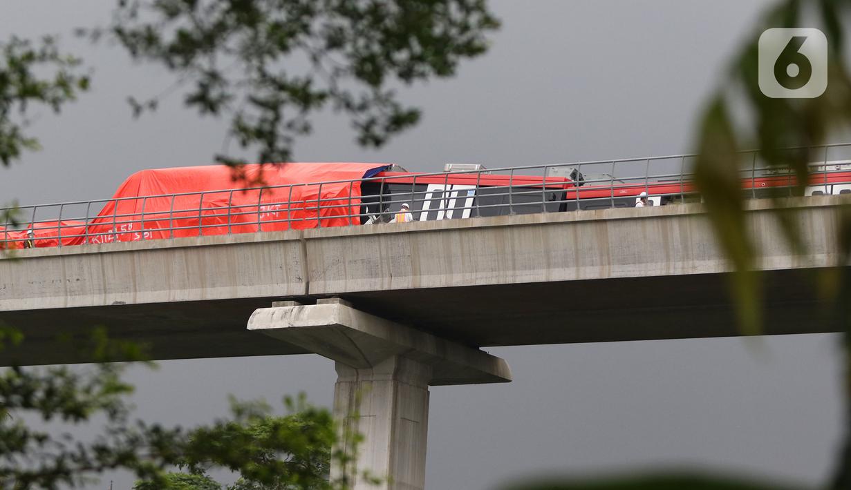 Petugas mengecek kereta ringan lintas rel terpadu (LRT) Jabodebek yang mengalami kecelakaan di jalur lintas LRT Cibubur, Jakarta Timur, Senin (25/10/2021). Petugas terlihat ada di rel untuk membantu proses evakuasi di mana bagian gerbong kereta ditutup terpal. (Liputan6.com/Herman Zakharia)