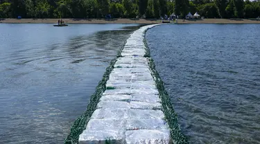 Warga memeriksa jembatan apung dari botol plastik yang ditempatkan di Danau Ada Ciganlija di Beograd, Serbia, Kamis, 27 Juli 2023. (AP Photo/Darko Vojinovic)