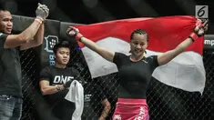 Petarung putri Indonesia, Priscilla Hertati Lumban Gaol membawa bendera merah putih usai mengalahkan petarung putri Malaysia, Audreylaura Boniface saat berlaga pada partai pertama One Championship di Jakarta, Sabtu (20/1). (Liputan6.com/Faizal Fanani)