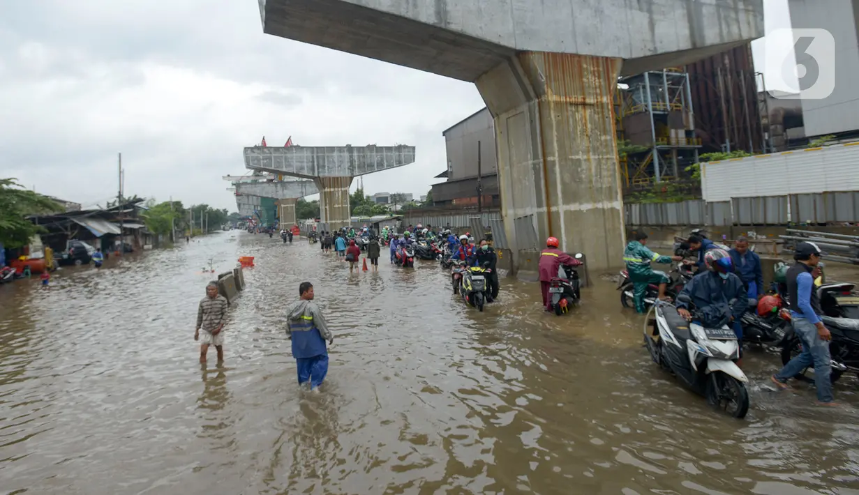 Pengendara mendorong motornya melintasi banjir di Jalan Raya Bekasi, Jakarta Timur, Selasa (25/2/2020). Banjir akibat hujan yang melanda Bekasi sejak Selasa (25/2) dini hari memutus beberapa titik jalan raya di wilayah setempat. (merdeka.com/Imam Buhori)