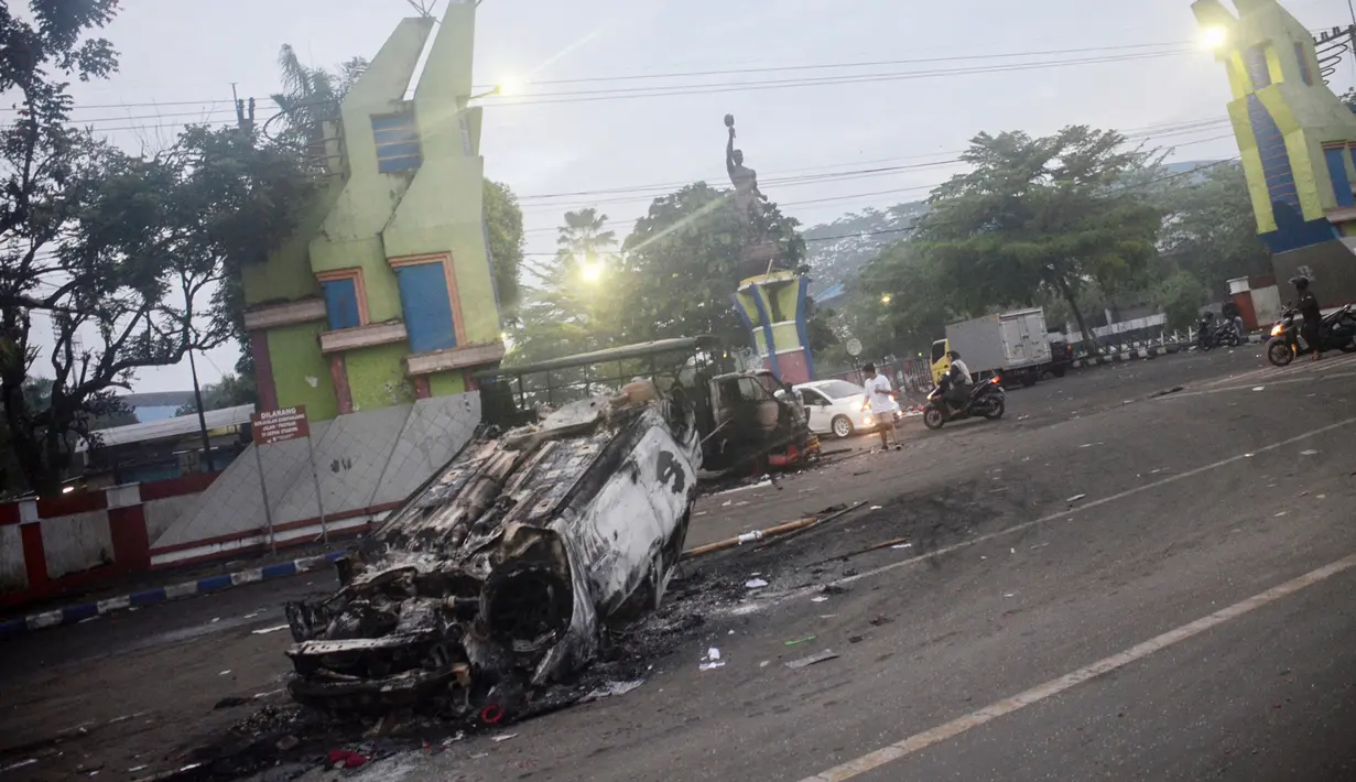 Mobil dibakar di luar Stadion Kanjuruhan, Malang, Jawa Timur, Minggu (2/10/2022). Sebanyak 127 orang tewas ketika para penggemar yang marah menyerbu lapangan sepak bola setelah pertandingan antara Arema FC dan Persebaya Surabaya pada 1 Oktober 2022. (PUTRI/AFP)