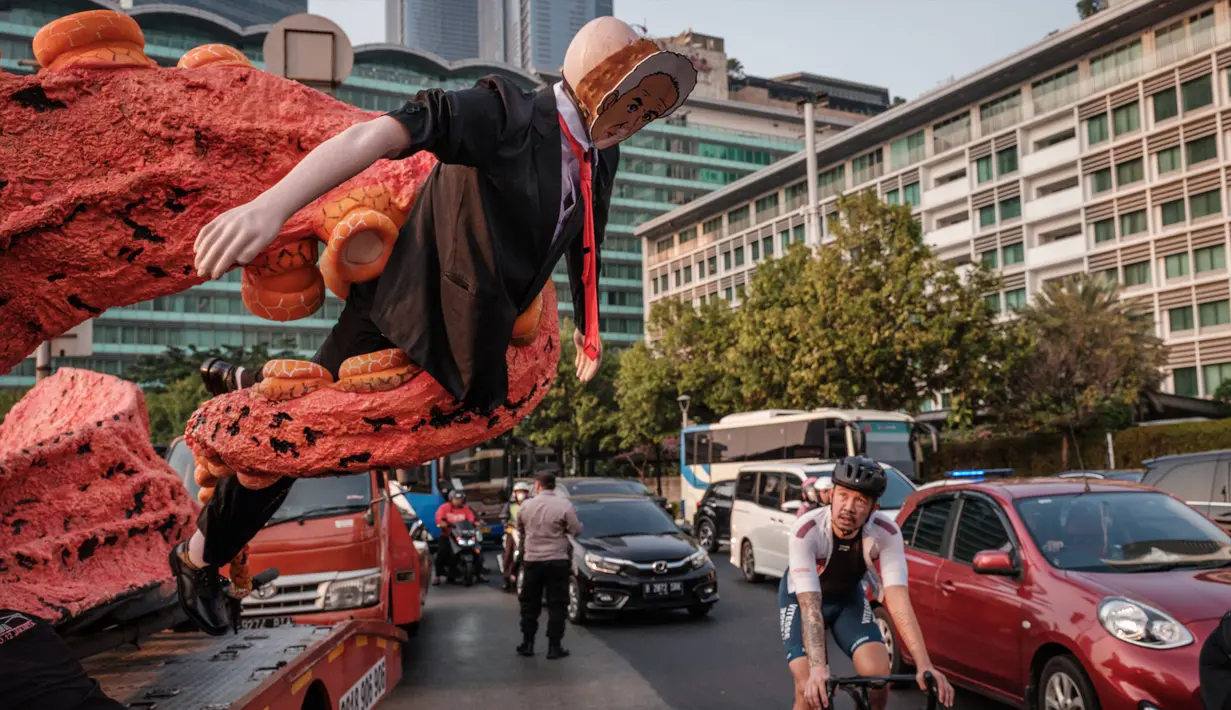 Seorang pengendara sepeda melewati sosok berbentuk gurita yang memegang manekin yang menyerupai seorang bakal calon presiden pada pemilu 2024 mendatang di kawasan Bundaran Hotel Indonesia, Jakarta, Jumat (6/10/2023). (Yasuyoshi CHIBA/AFP)