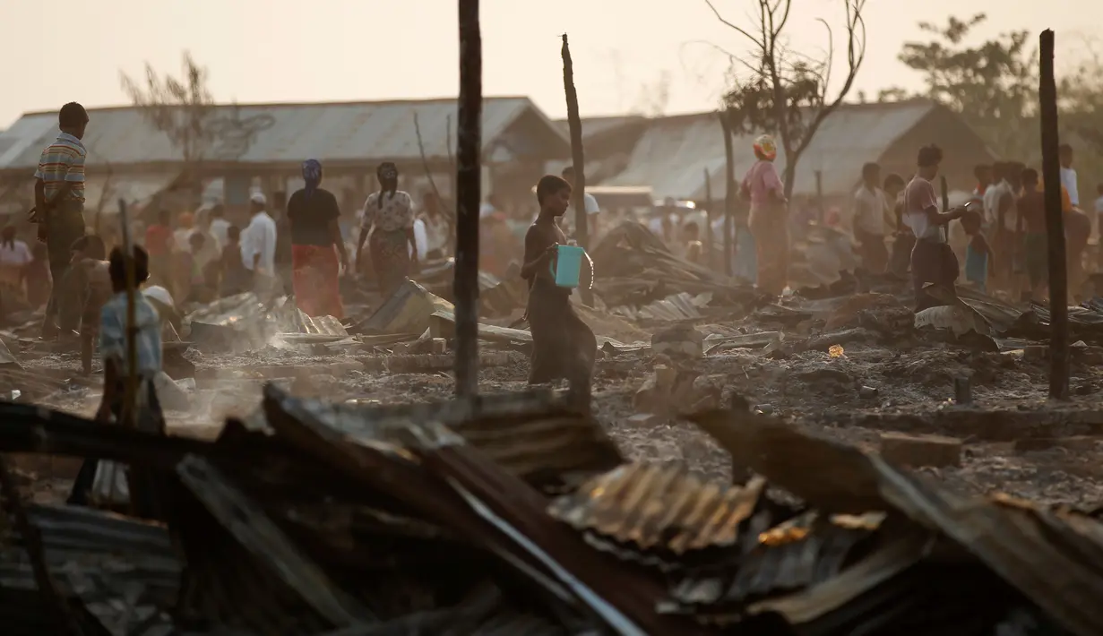 Orang-orang berdiri di antara puing-puing setelah kebakaran sebuah kamp bagi pengungsi Muslim Rohingya di negara bagian Rakhine, Myanmar, Selasa (3/5). Kebakaran menghancurkan 50 hunian sementara dalam kamp bagi pengungsi asing. (REUTERS/Soe Zeya Tun)