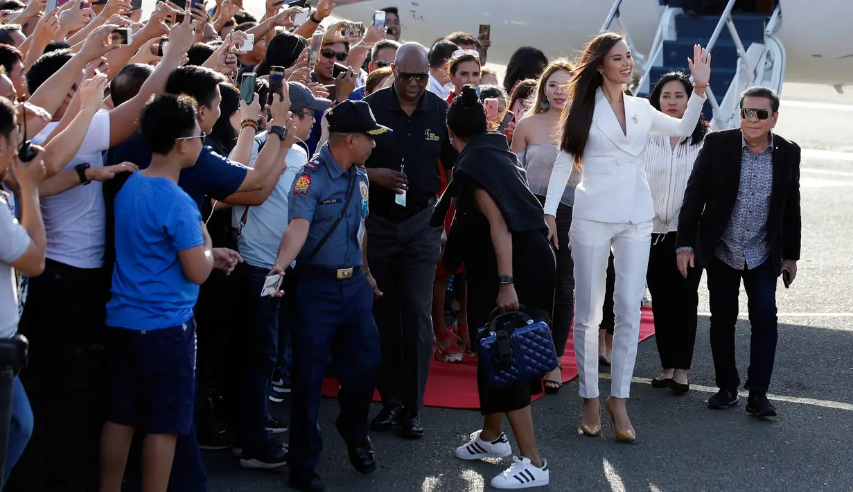 Miss Universe 2018 Catriona Grey melambaikan tangan saat tiba di Manila, Filipina, Rabu (19/12). Wanita keturunan Skotlandia-Filipina itu tiba dengan menggunakan jet pribadi. (AP Photo/Aaron Favila)