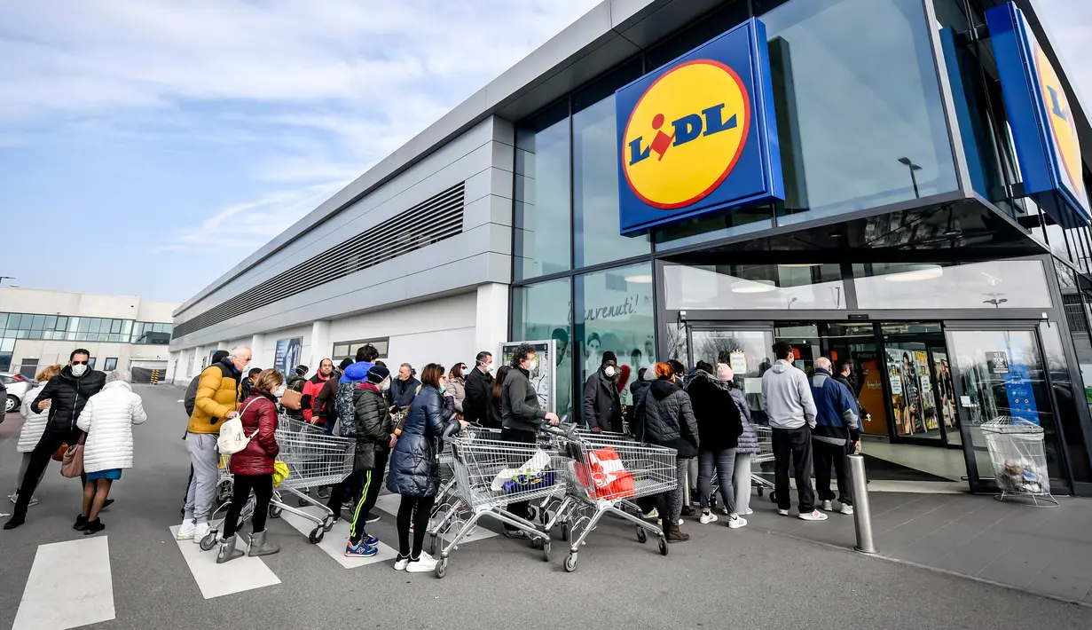 Orang-orang mengenakan masker antre di luar sebuah supermarket di Casalpusterlengo, Minggu (23/2/2020). Mereka memborong perlengkapan dan bahan-bahan kebutuhan pokok karena tak mau keluar rumah menyusul dua warga Italia yang meninggal karena Virus Corona COVID-19. (Claudio Furlan/Lapresse via AP)