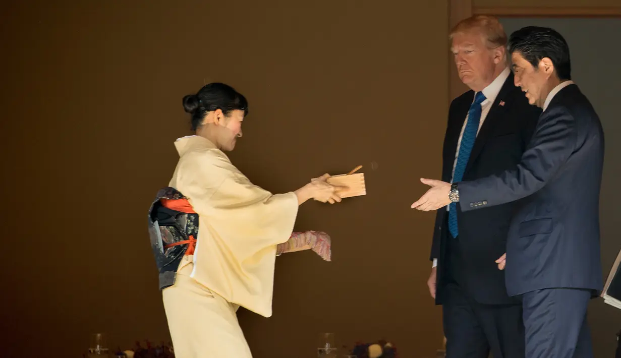 Presiden AS Donald Trump dan PM Jepang Shinzo Abe menerima kotak makanan ikan saat akan memberi makan koi di kolam Istana Akasaka, Tokyo, Senin (6/11). Beragam momen terlihat dalam kunjungan Presiden Donald Trump ke Jepang. (AP/Andrew Harnik)