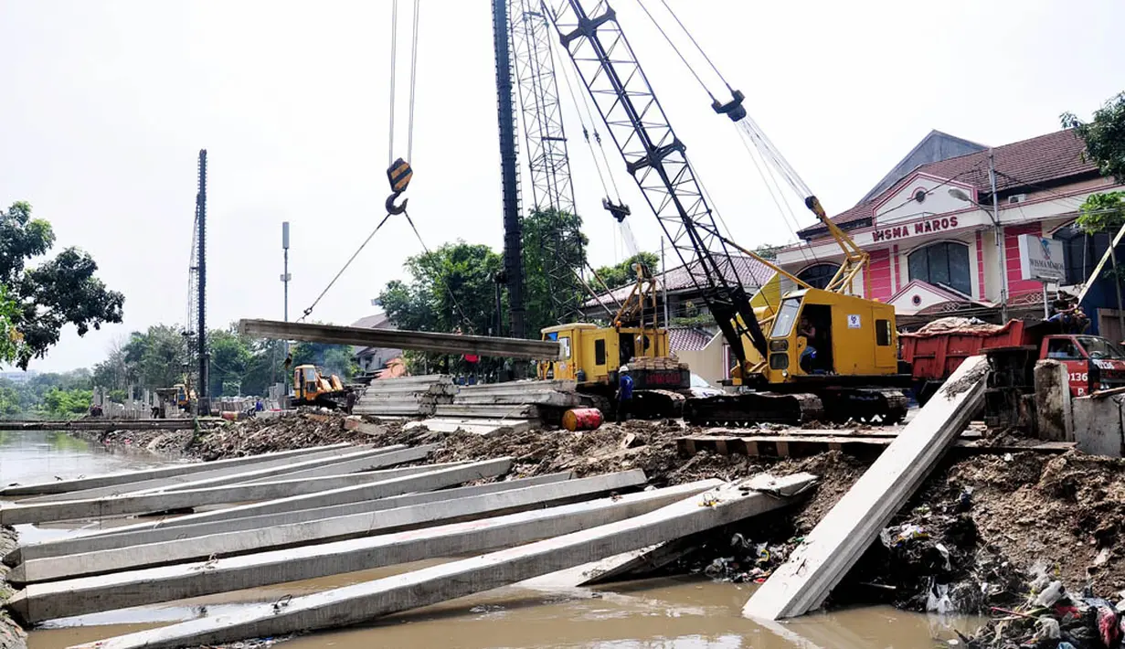 Pekerja menggunakan kendaraan alat berat untuk memasang beton saat mengerjakan proyek pembangunan turap Kali Utan Kayu, Jakarta, Selasa (17/6/14). (Liputan6.com/Faizal Fanani)