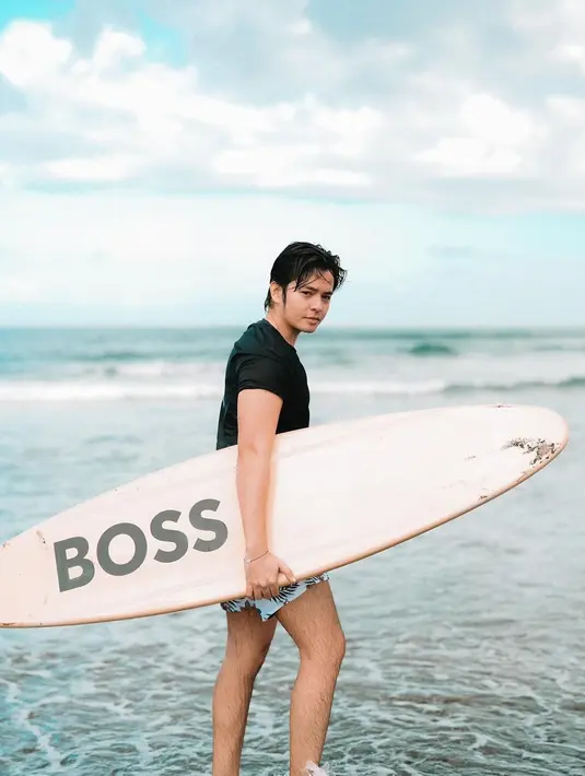 Angga Yunanda memang sedang melakukan sesi pemotretan. Biasa tampil di studio, ketampanan Angga Yunanda saat pegang papan selancar ini makin membuatnya menawan. (Liputan6.com/IG/@angga)