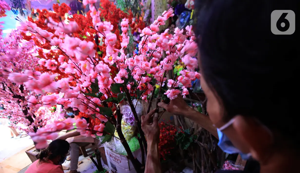 Pedagang saat membuat pohon bunga Meihua di salah satu toko Asemka, Glodok, Jakarta, Rabu (3/2/2021). Namun dimasa pandemi, penjualan bunga ini berkurang dikarenakan banyak pembeli yang lebih memilih pembelian online. (Liputan6.com/Johan Tallo)