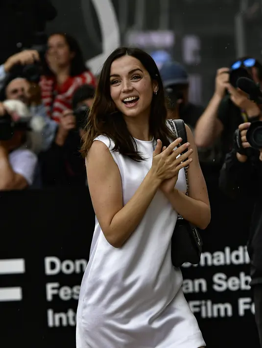 Ana de Armas tersenyum saat tiba menghadiri Festival Film San Sebastian ke-70, di San Sebastian, Spanyol utara (23/9/2022). Ana menunjukkan senyum lebarnya dengan penampilnya mengenakan sepasang anting-anting kecil berwarna emas. (AP Photo/Alvaro Barrientos)