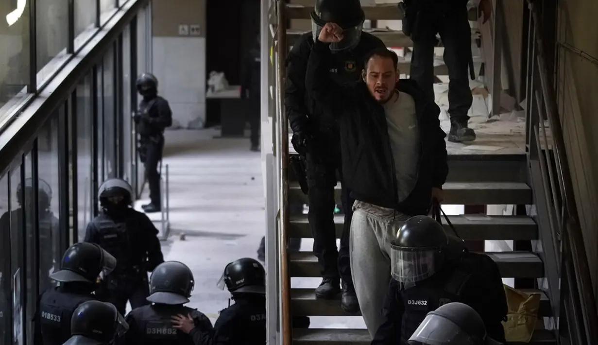 Rapper Pablo Hasel ditahan oleh petugas polisi di Universitas Lleida, Spanyol, Selasa (16/2/2021). Kebuntuan selama 24 jam antara polisi dan Pablo Hasel yang dibarikade dengan puluhan pendukungnya di sebuah universitas berakhir dengan penangkapan. (AP Photo/Joan Mateu)
