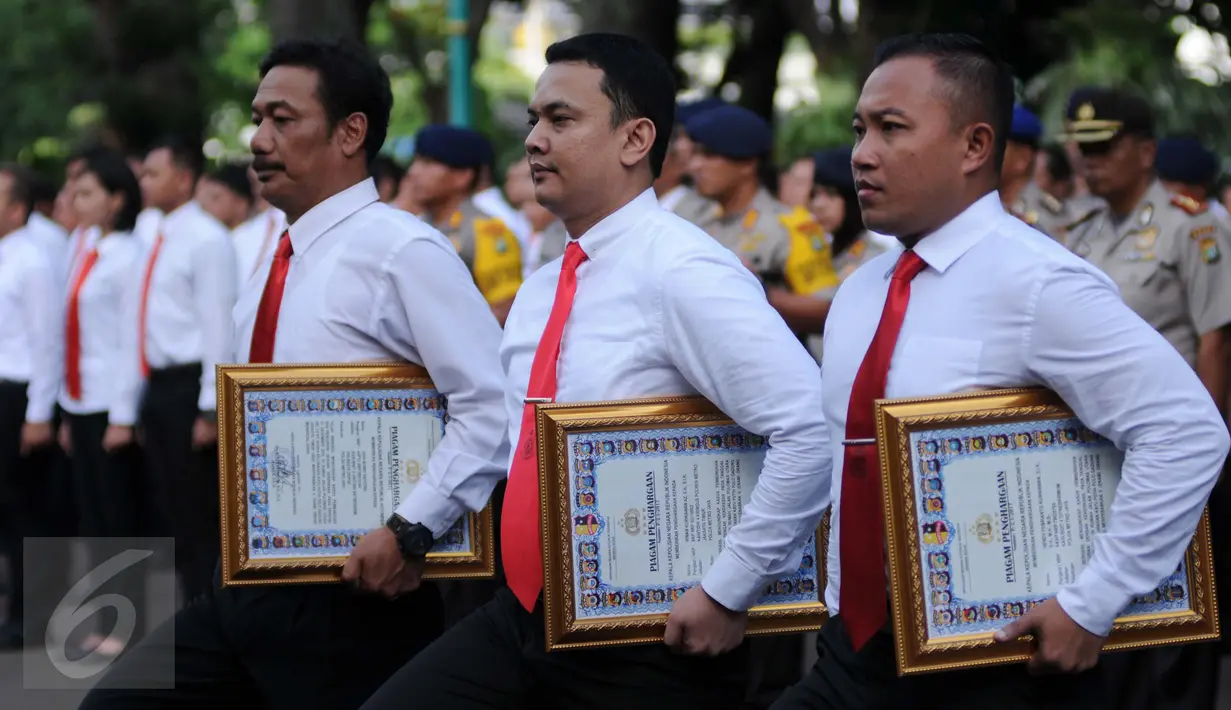Anggota kepolisian membawa piagam penghargaan dari Kapolri di Polda Metro Jaya, Jakarta, Rabu (18/1). Penghargaan diberikan atas prestasi pengungkapan kasus perampokan Pulomas dengan cepat. (Liputan6.com/Gempur M Surya)