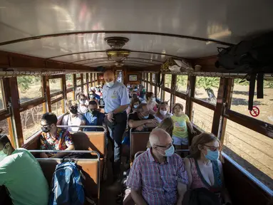 Inspektur Manolo Toncho berjalan melewati penumpang yang menaiki kereta Palma-Soller di Palma de Mallorca di Kepulauan Balearic Spanyol (14/7/2021). Diresmikan pada tahun 1912, jalur kereta api Palma-Soller adalah salah satu rute tertua yang masih beroperasi di Spanyol. (AFP/Jaime Reina)