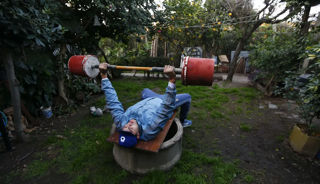 Yamil Peralta mengangkat barbel dari semen di belakang rumahnya di Jose C. Paz di pinggiran Buenos Aires, Argentina, 29 Juli 2020. Di tengah lockdown COVID-19, petinju Olimpiade dan profesional ini mendapat pekerjaan di perusahaan sampah untuk memenuhi kebutuhannya. (AP Photo/Marcos Brindicci)