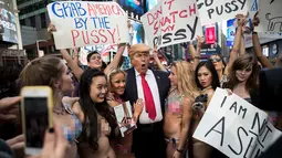 Sejumlah wanita seksi berbikini mengililingi seniman berpenampilan seperti Donald Trump saat unjuk rasa di depan Times Square, New York (25/10). Aksi ini dilakukan oleh seniman Alison Jackson. (AFP Photo/Drew Angerer/Getty Images)