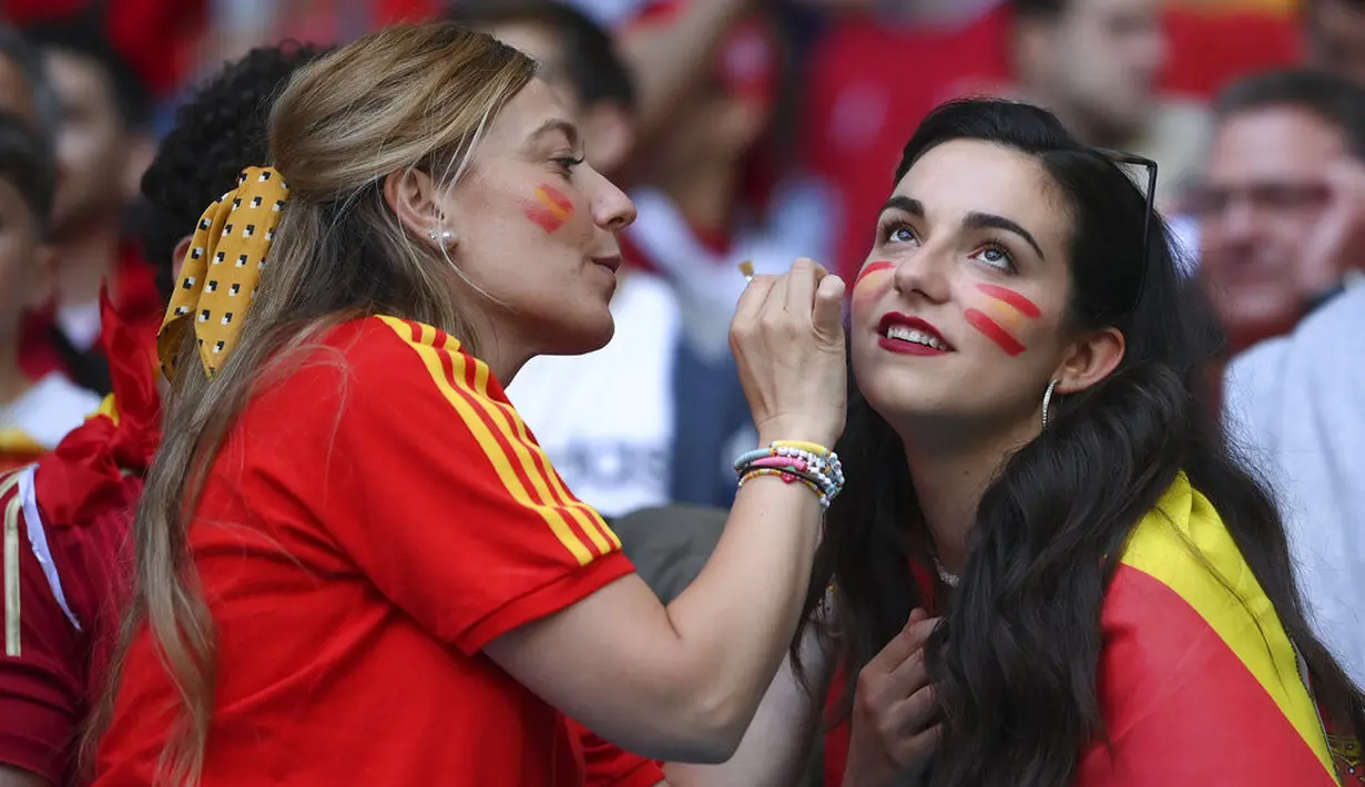 Fans wanita mengecat muka bendera Spanyol sebelum dimulainya pertandingan semifinal EURO 2020 antara Italia dan Spanyol di Stadion Wembley di London (7/7/2021). (Andy Rain/Pool via AP)