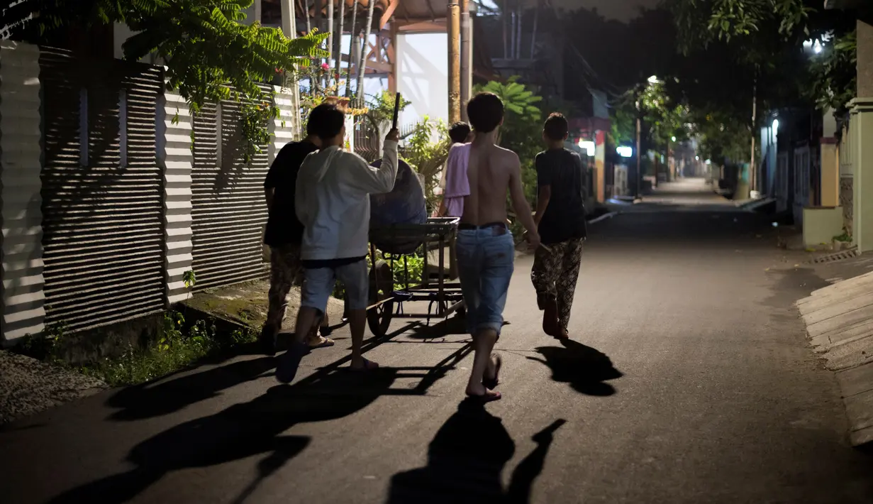 Sejumlah pemuda berusaha membangunkan warga untuk melaksanakan sahur sekitar lingkungan mereka di Jakarta, 19 Mei 2018.  Kegiatan yang dilakukan menjelang sahur tersebut menggunakan tong dan tempat cat bekas. (AFP PHOTO/BAY ISMOYO)