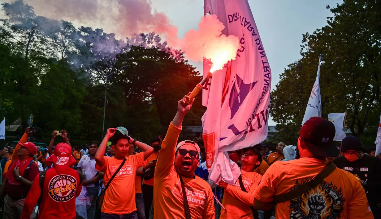 Seorang pengunjuk rasa menyalakan suar dalam aksi unjuk rasa peringatan Hari Buruh Internasional (May Day) di Surabaya, Jawa Timur, pada Kamis 1 Mei 2025. (Juni KRISWANTO/AFP)