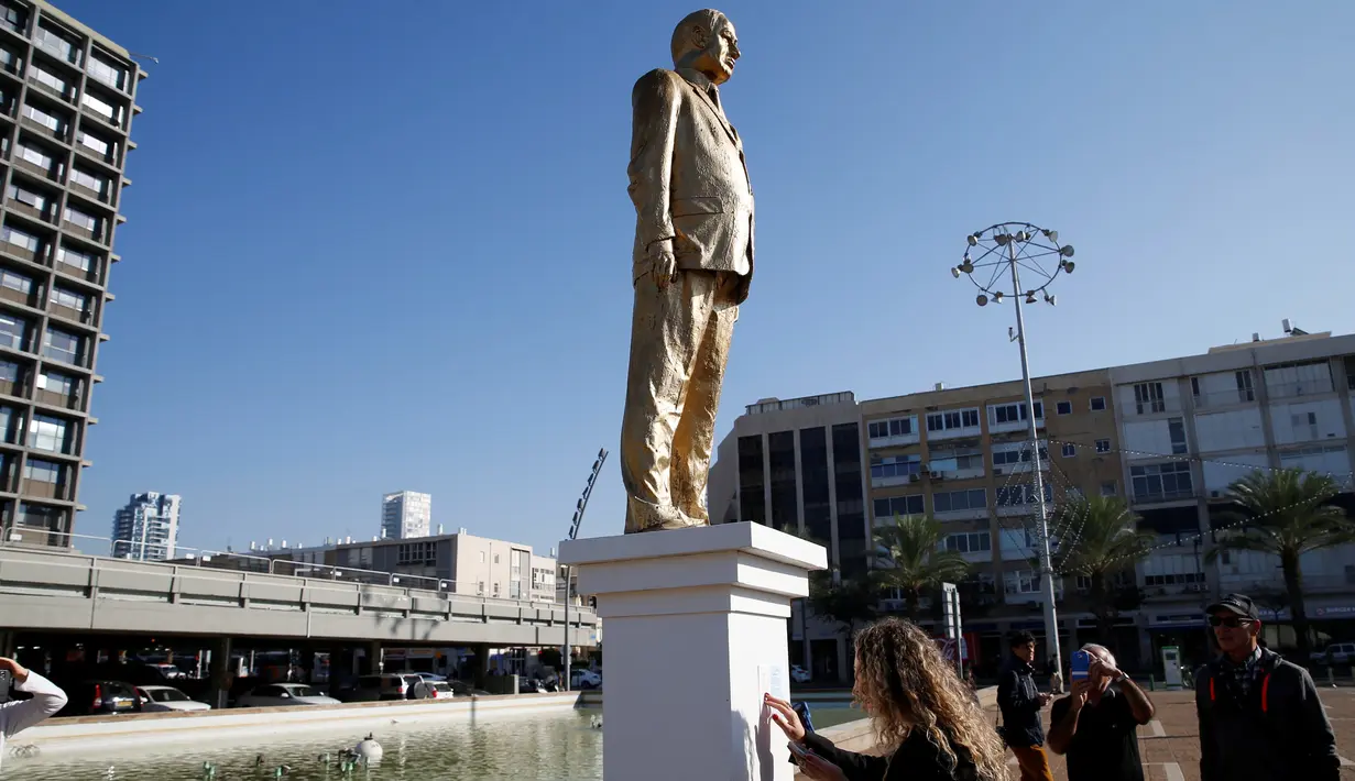 Warga melihat dan mengabadikan patung emas raksasa PM Israel Benjamin Netanyahu di tengah-tengah Rabin Square, Tel Aviv, Selasa (6/12). (REUTERS / Baz Ratner)