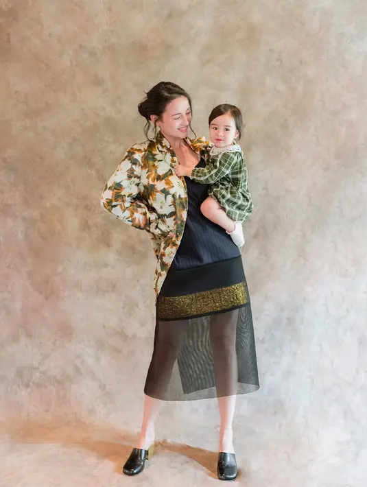 Dengan nuansa hijau, gayanya begitu menggemaskan. Sang anak kenakan dress bersiluet klasik disertai motif tartan yang menggemaskan. [Foto: Instagram/ Julie Estelle]