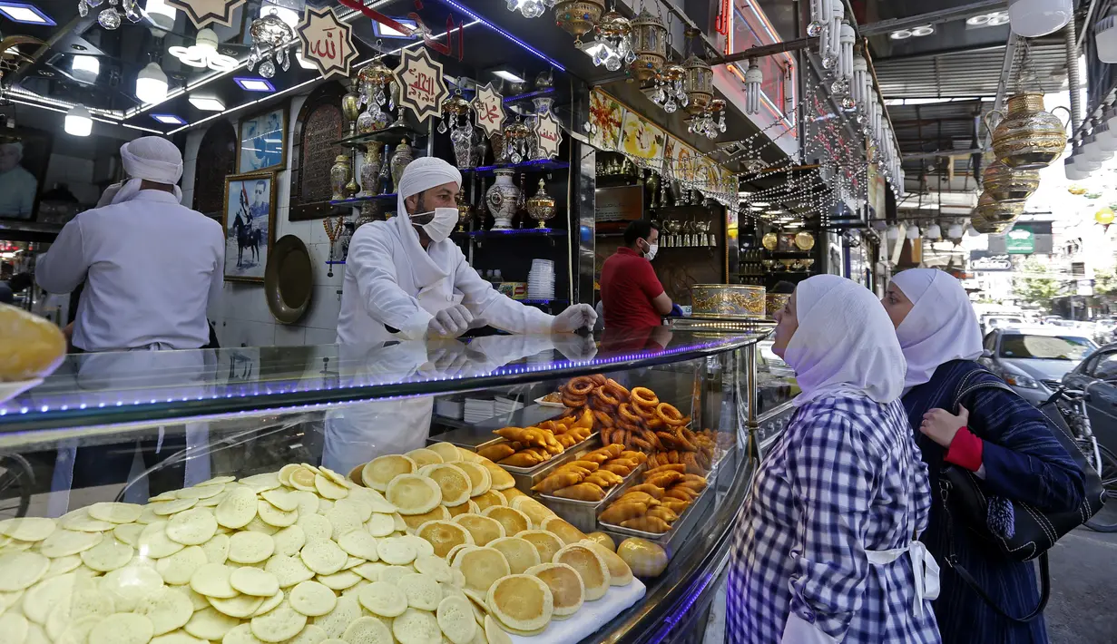 Warga membeli kudapan untuk berbuka puasa selama bulan suci Ramadan di Pasar Maidan, Damaskus, Suriah, Senin (26/4/2020). (Photo by LOUAI BESHARA/AFP)