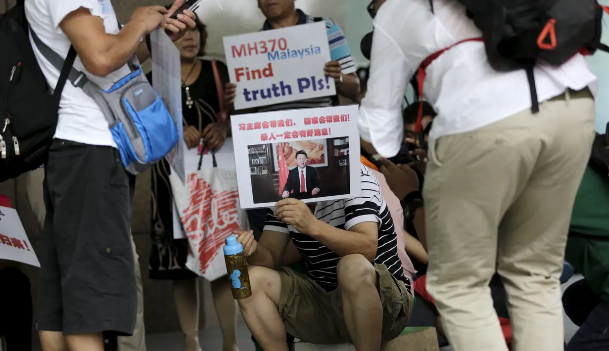 Salah satu keluarga penumpang MH370 membawa poster saat menggelar aksi di depan kantor Malaysia Airlines, Beijing, Kamis (6/8). Pemerintah Malaysia telah resmi menyatakan puing pesawat di Pulau Reunion adalah bagian dari MH370. (REUTERS/Jason Lee)