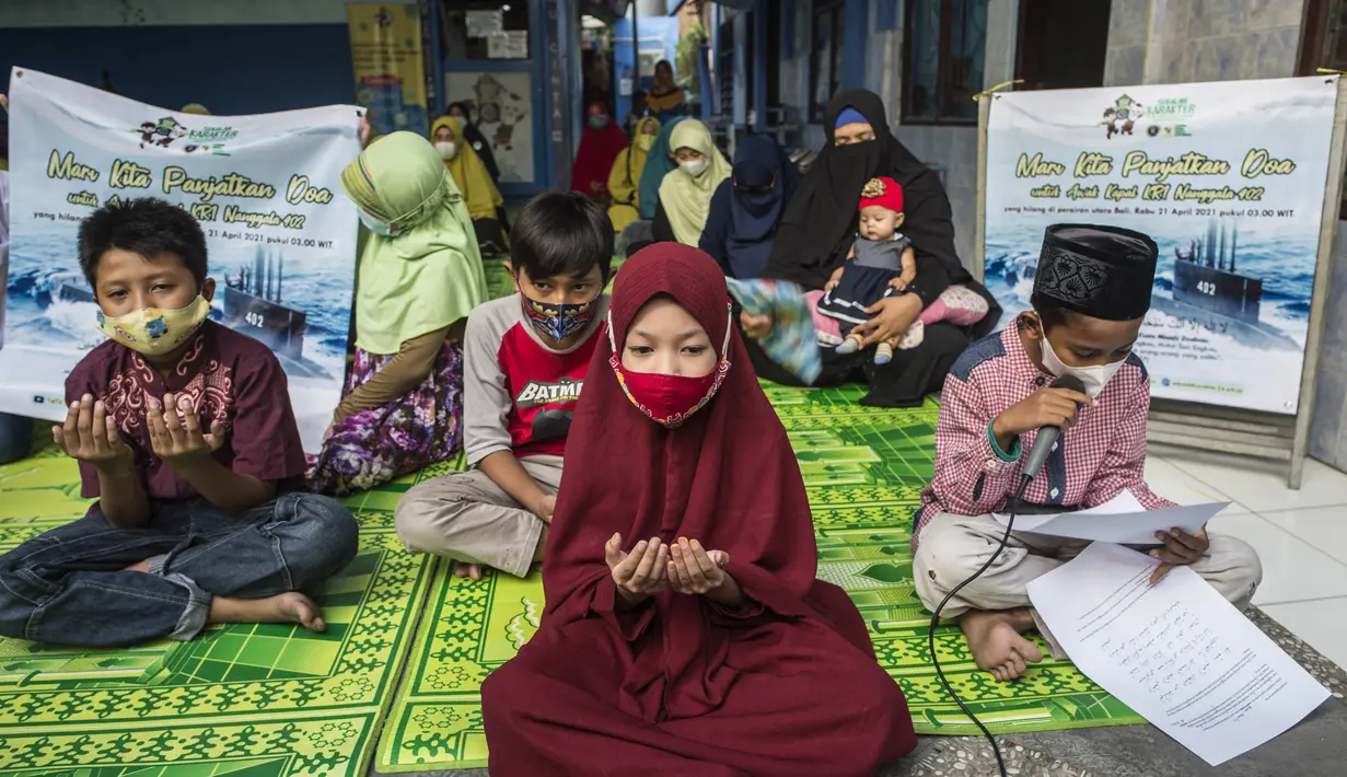 Siswa dan guru berdoa untuk 53 awak kapal selam KRI Nanggala 402 yang hilang di perairan Bali, di sebuah sekolah Islam di Surabaya, Jumat (24/4/2021). Kapal selam KRI Nanggala-402 yang membawa 53 awak dilaporkan hilang kontak di perairan Bali, Rabu, 21 April kemarin. (Juni Kriswanto/AFP)