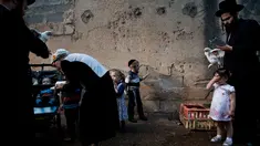 Pria Yahudi ultra-Ortodoks mengayunkan ayam memutari kepala anak-anak dalam ritual Kaparot di Bnei Brak, Israel, Minggu (16/9). Ayam ini kemudian akan disembelih menjadi pengganti seseorang tersebut sebagai penebusan untuk dosa-dosanya. (AP/Oded Balilty)