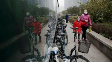 Seorang wanita membawa anak berjalan memakai masker menuju sekolah pada pagi hari di Yanjiao, provinsi Hebei, Cina (13/11). Selama lima hari ini Cina mengalami kualitas udara yang menurun karena tercemar polusi. (REUTERS/Damir Sagolj)