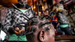 Gettrueth Ambio (12) rambutnya ditata dengan model yang terinsprasi dari corona Covid-19 oleh Mama Brayo Beauty Salon di daerah kumuh Kibera, Kenya, 3 Mei 2020. Corona telah menghidupkan kembali gaya rambut di Afrika Timur yang memiliki lonjakan kepang bentuk khas virus. (AP/Brian Inganga, File)