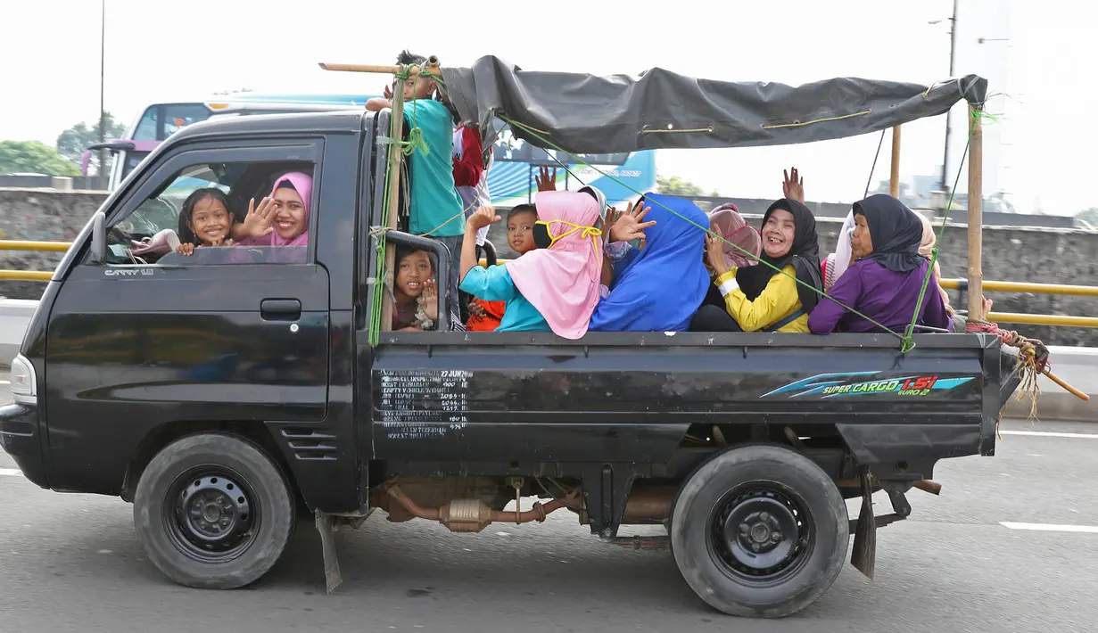 Sejumlah warga berpergian dengan menggunakan mobil bak terbuka di kawasan Jakarta, Minggu (9/6/2019). Warga memanfaatkan truk dan mobil bak terbuka untuk bepergian bersama keluarga menuju sejumlah objek wisata karena dianggap lebih hemat biaya. (Liputan6.com/Herman Zakharia)