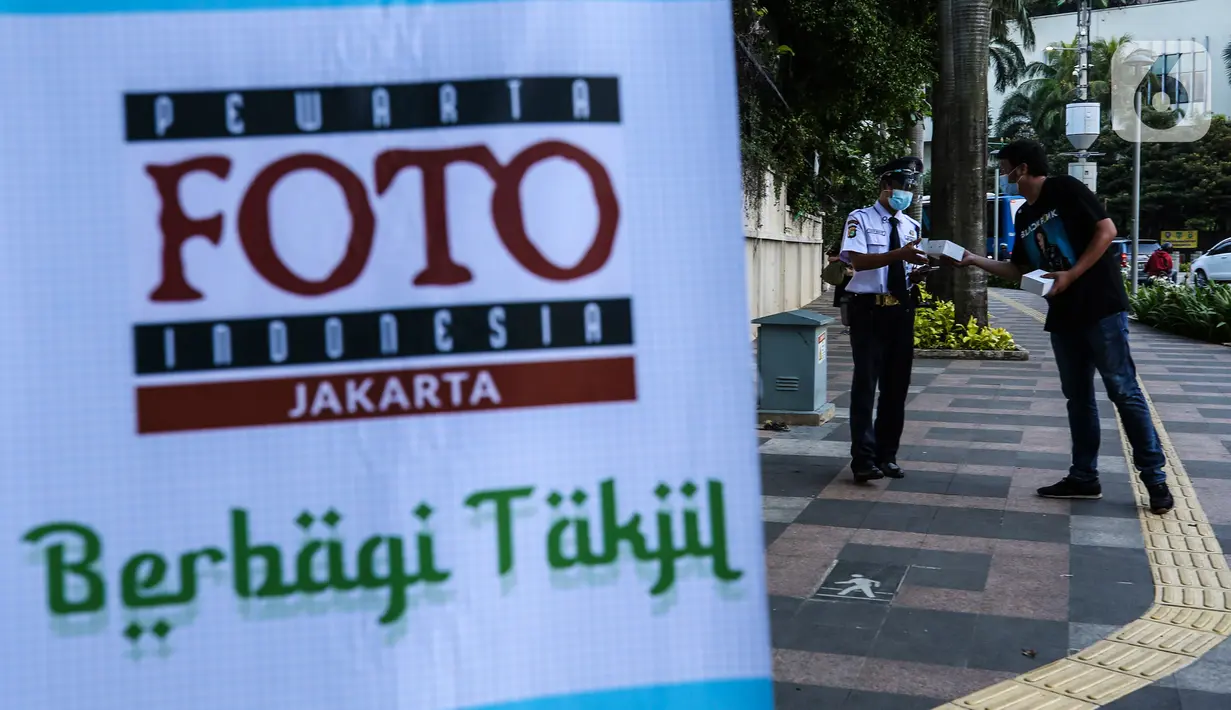 Pewarta Foto membagikan takjil kepada pejalan kaki di Kawasan Bundaran HI, Jakarta, Selasa (20/4/2021). Kegiatan berbagi takjil yang digagas oleh Pewarta Foto Indonesia Jakarta (PFIJ) ini dilaksanakan setiap hSelasa dan Jumat selama bulan Ramadhan sebagai bentuk solidaritas (Liputan6.com/JohanTallo)